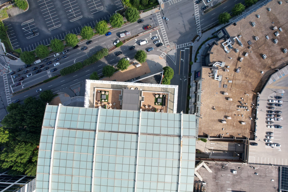 Overhead view of a commercial rooftop, parking areas, and a nearby road intersection.